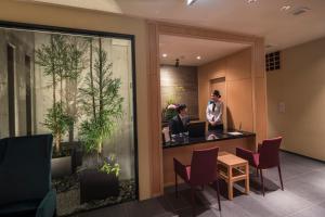 zwei Personen stehen an der Rezeption in einer Lobby in der Unterkunft Kyoto Shinmachi Rokkaku Hotel grandereverie in Kyoto