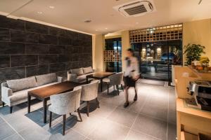 京都市にある京都 新町六角ホテル グランレブリーのテーブルと椅子のあるレストランを通り抜ける者