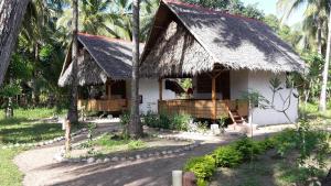 a white house with a thatched roof and palm trees at Sugar Lounge Lodge in Nauhang
