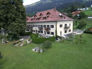 a large white building with a red roof on a green field at Garten- & Loggia-Appartement HERRENHAUS in Dellach im Drautal