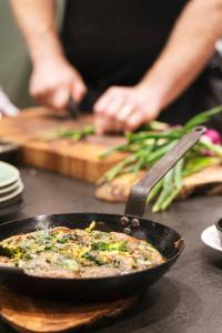 a person cooking food in a pan on a table at Hotel St. George Helsinki in Helsinki