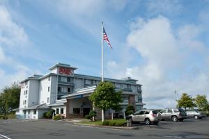 a hotel with an american flag on a pole in a parking lot at Shilo Inn Suites Warrenton in Warrenton