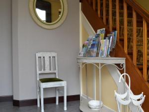une chaise et une table avec des livres et un miroir dans l'établissement Spacious Cottage in Thirimont near Forest, à Waimes