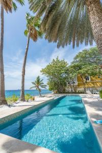 a swimming pool with palm trees and the ocean at Sirena Bay Estate in Willemstad