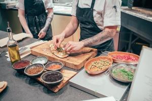 a chef preparing food on a cutting board in a kitchen at Hotel St. George Helsinki in Helsinki