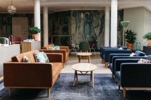 a waiting area with couches and tables in a salon at Hotel St. George Helsinki in Helsinki
