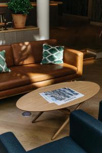 a brown leather couch sitting on top of a wooden coffee table at Hotel St. George Helsinki in Helsinki