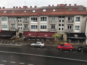 dos coches estacionados en una calle frente a los edificios en Apartamento Good Way, en O Pedrouzo