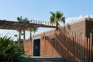 a building with a wooden fence and palm trees at Nova Lodges in Grimaud