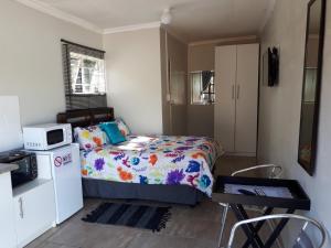 a small bedroom with a bed and a microwave at 8 Soenie Avenue Self Catering in Pretoria