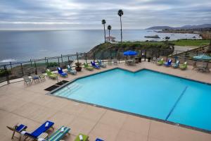 una piscina con sillas y el océano en el fondo en Shore Cliff Hotel, en Pismo Beach