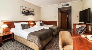 a hotel room with two beds and a television at Airport Hotel Okęcie in Warsaw