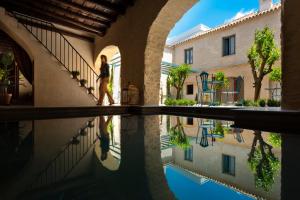 a woman walks through an arcade next to a pool of water at Palacio Bucarelli in Seville