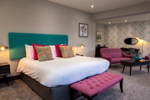 a bedroom with a large bed and pink chairs at Hawkstone Park in Wem