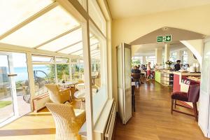 a restaurant with tables and chairs in a room with windows at Villa Mentone Hotel in Shanklin