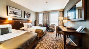 a hotel room with two beds and a desk at Airport Hotel Okęcie in Warsaw