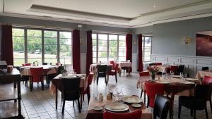 a dining room with tables and chairs and windows at Hôtel Restaurant du Lac in Combourg
