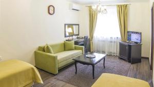 sala de estar con sofá verde y TV en Russkaya Okhota Hotel, en Kurumoch
