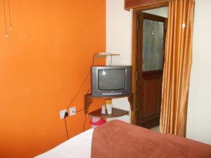 a bedroom with a tv and an orange wall at Premier rooms with Rooftop Terrace Restaurant in Nainital