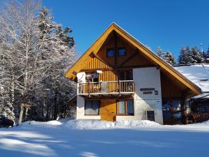 a log cabin with a balcony in the snow at Auberge Refuge de Roybon in Saint-Martin-en-Vercors