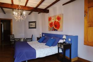 Un dormitorio con una cama azul y una lámpara de araña. en Trisileja en Posada La Busta, en La Busta