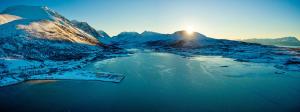 an aerial view of a snow covered mountain with a lake at Lyngen Experience Apartments in Nord-Lenangen