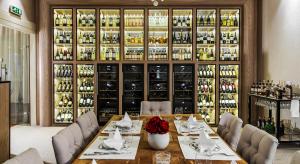 a dining room with a table and chairs and a wall of wine bottles at Airport Hotel Okęcie in Warsaw