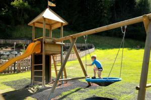a young boy playing on a swing set on a playground at Hüttendorf Schladming in Schladming