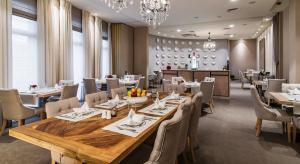 a restaurant with a large wooden table and chairs at Airport Hotel Okęcie in Warsaw