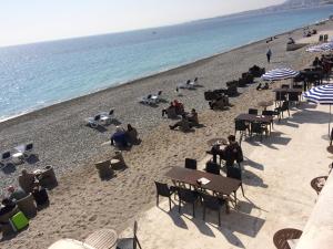 a group of people sitting at tables on a beach at Hotel Suisse in Nice