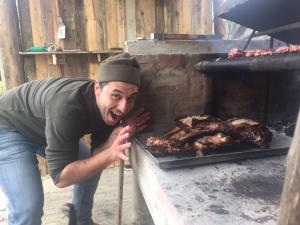 a man standing next to a grill with meat at Agriturismo Il Picchio Verde in Licciana Nardi