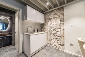 a kitchen with a sink and a stone wall at Alma Lofts in Zadar