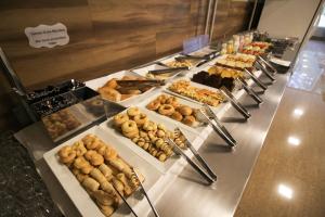 uma linha de buffet com muitos tipos diferentes de pastelarias em Impar Suites Barao de Cocais em Barão de Cocais