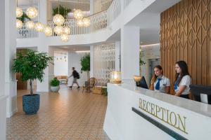 two women sitting at a reception desk in a lobby at Sunrise Blue Magic Resort - All Inclusive in Obzor +37 photos