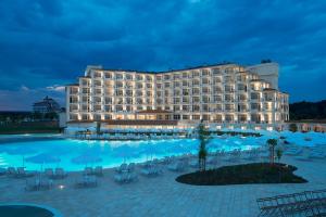 a hotel with a large pool at night at Sunrise Blue Magic Resort - All Inclusive in Obzor