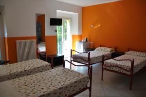 a room with three beds and a tv in it at Ostello Residenza Molinatto in Oggiono
