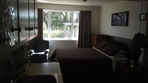 a bedroom with a bed and a window and a chair at Orchard Queen Motel & Rv Park in Middleton