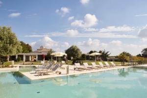 einen großen Pool mit Liegestühlen und Sonnenschirmen in der Unterkunft Borgo di Luce I Monasteri Golf Resort & SPA in Syrakus