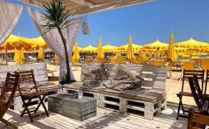 eine Terrasse mit einem Sofa, Stühlen und Sonnenschirmen in der Unterkunft Hotel Caravan B&B in Pesaro