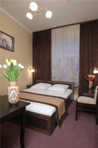 a bedroom with a bed with a window and a vase of flowers at Eliseeff Arbat Hotel in Moscow