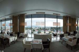 Grand Plaza Hotel Nampula في نامبولا: مطعم بطاولات وكراسي ونوافذ كبيرة