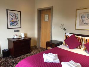 a bedroom with a large bed with a pink blanket at Marine Hotel in Hunstanton