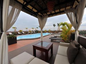 a patio with white furniture and a swimming pool at City River Hotel in Siem Reap