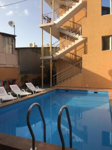 a swimming pool with chairs and a building at Guest House Mikhail in Adler