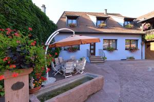 a house with a patio with an umbrella and chairs at S'Harzala Bleu in Bergheim