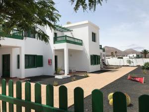 a white house with green gates and a fence at Apartamentos Flamboyant Adults Only in Puerto del Carmen