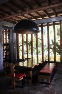 uma sala de jantar com uma mesa de madeira e uma luz pendente em Waterstone Guesthouse em Bukit Lawang