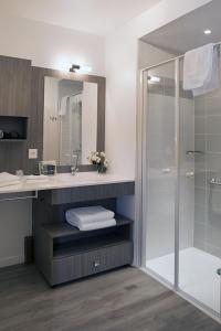 bagno con doccia, lavandino e specchio di Domitys Le Griffon d’Or a Saint-Brieuc