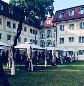 eine Reihe von Tischen mit Sonnenschirmen vor einem Gebäude in der Unterkunft Hotel Holiday Park in Warschau