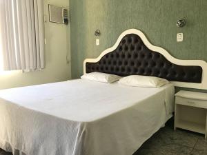 a large bed with a large headboard in a bedroom at Hotel Meri in Conselheiro Lafaiete